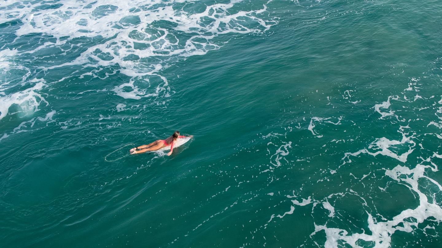 A woman riding a surfboard on top of a wave in the ocean